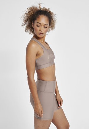Bruin sportieve crop top en bijpassende high-waisted shorts, gemaakt van glad, rekbaar materiaal. Heeft een logo op de voorkant.
