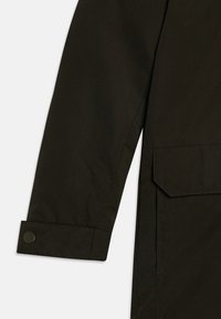 Tmavě zelená rukávová bunda s knoflíkovým manžetou a boční kapsou s detailním šitím, vyrobená z hladkého, odolného materiálu.