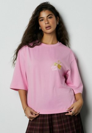 Pink oversized t-shirt made of cotton, featuring short sleeves and a round neckline. Embroidered "Slow Down" with floral accents.