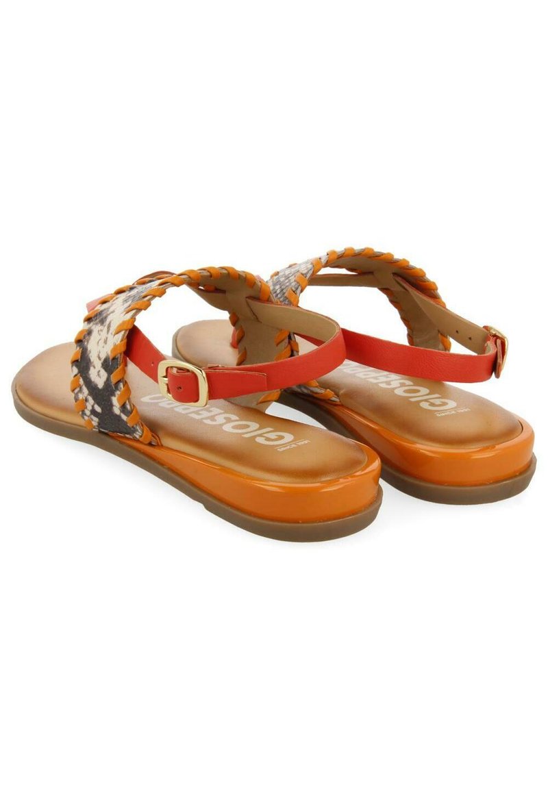 Orangefarbene flache Sandalen mit geflochtenen Riemen, die ein gemustertes Design aufweisen und über einen Schnallenverschluss verfügen. Die Sohle ist glatt und glänzend.