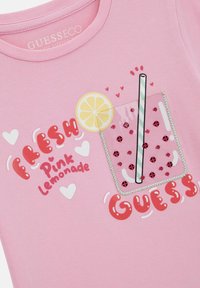 Rosa Baumwoll-T-Shirt mit Grafik eines Glases mit einem Zitronenscheibe, einem Strohhalm und roten dekorativen Elementen, mit dem Text "FRISCH Pinke Limonade."