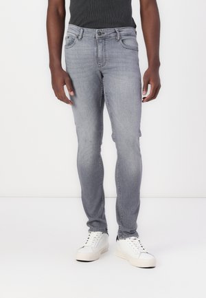 Slim-fit grey jeans made of denim, featuring a button closure and five pockets. Paired with white sneakers, displayed against a plain background.