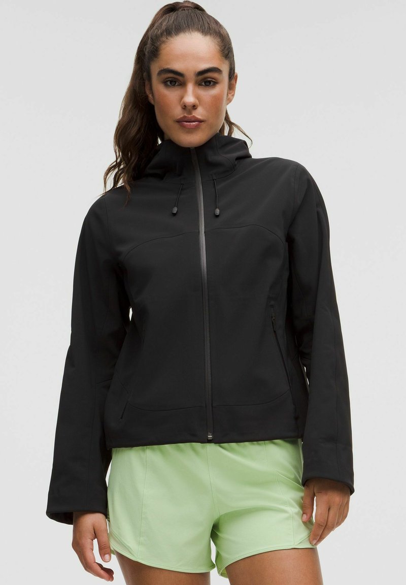 Must must jacket, millelukuga, reguleeritava kapuutsiga ja küljetaskutega, koos helesiniste lühikestega. Sile, mati tekstuuriga.