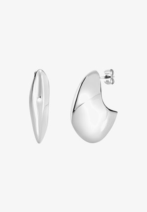 Zakrecone srebrne kolczyki o gładkiej, odbijającej światło powierzchni. Jeden kolczyk ma kształt łezki, a drugi zaokrągloną, asymetryczną formę.