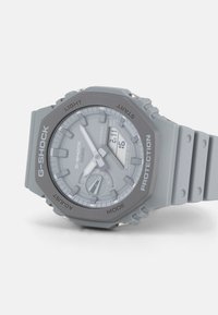G-SHOCK watch with a gray resin case and strap, digital and analog display, round face, large buttons, water resistance 20BAR.