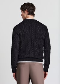 Schwarzer Pullover mit Zopfmuster, gerippten Bündchen und Saum, über einem weißen Hemd getragen, von hinten vor einfachem Hintergrund gezeigt.