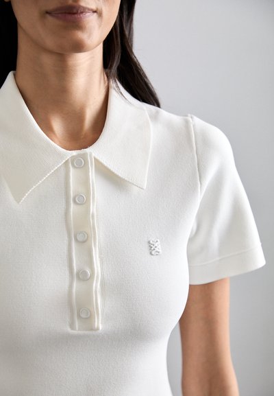 Witte gebreide polo-shirt met een col-nek, korte mouwen en een knoopsluiting met vijf knopen. Klein logo op de borst.