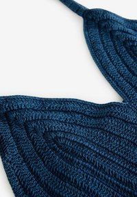 Tissu crocheté bleu foncé formant des formes triangulaires avec des points texturés et concentriques et une fine sangle qui s'étend depuis le coin supérieur.