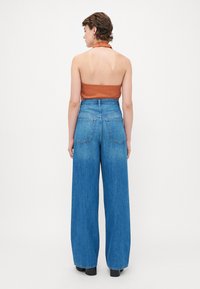 Høyt liv, vid ben blå denim jeans med falmet finish, med to baklommer og en strukturert midjebånd.
