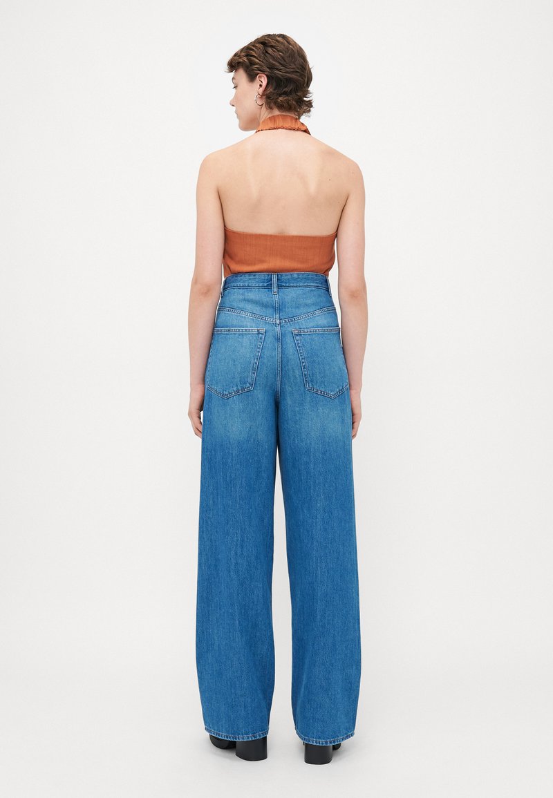 Jeans z wysokim stanem i szerokimi nogawkami w niebieskim odcieniu, z wyblakłym wykończeniem, wyposażone w dwie tylne kieszenie i usztywniony pas.