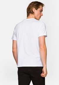 Biała bawełniana koszulka z krótkim rękawem, okrągłym dekoltem i gładkim tyłem. Brak widocznych wzorów lub akcentów.