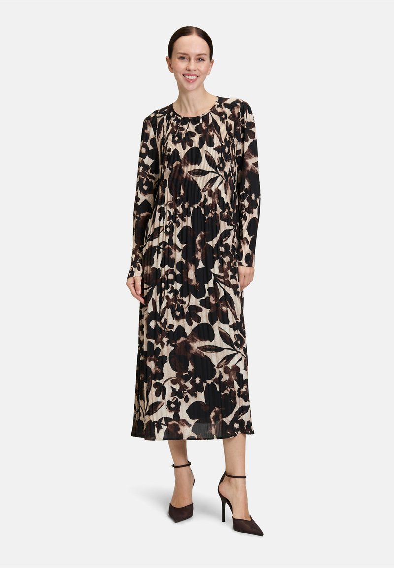 Langärmliges Kleid mit floralem Muster in Braun und Schwarz auf beigem Hintergrund, mit plissierter Textur und lockerer Passform.