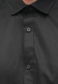 Zwart shirt met een klassieke kraag, gemaakt van gladde stof, met een rij zwarte knopen en een subtiele textuur op het oppervlak.