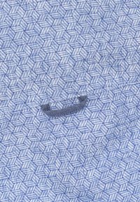 Blauwe stoffen met een geometrisch hexagonaal patroon en een textuur die op linnen lijkt. Bevat een kleine zwarte stoflus om op te hangen.