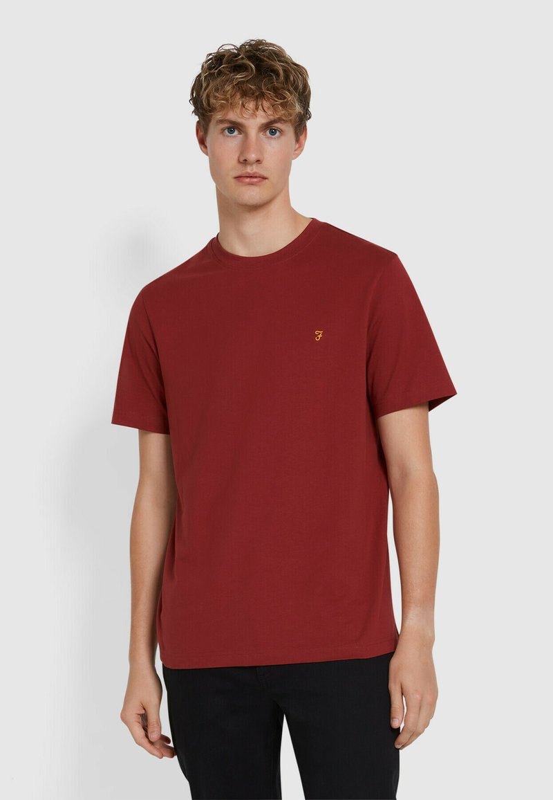 T-shirt in cotone rosso con maniche corte, collo rotondo e un piccolo logo giallo sul petto. Tessuto liscio e vestibilità comoda.