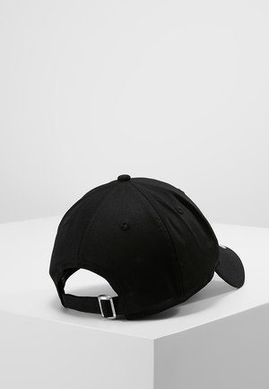 Czarna regulowana czapka bejsbolowa z metalową klamrą na białej kanciastej powierzchni na jednolitym jasnoszarym tle.