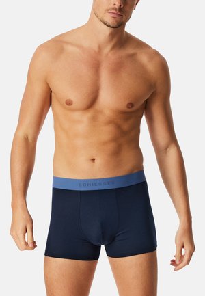 Boxers en bleu marine en tissu doux, avec une ceinture élastique bleu clair portant le texte "SCHIESSER" en gris. Design ajusté.