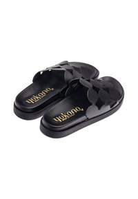 Chanclas negras con diseño floral recortado, plantilla texturizada y logo dorado. Fabricadas con material suave, cuentan con una suela de perfil bajo.
