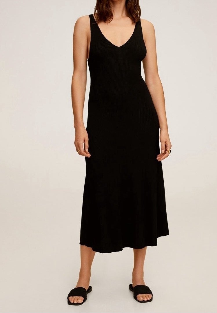 Robe midi noire, sans manches, en tissu côtelé, avec un col en V, un ourlet évasé et une texture lisse, associée à des sandales plates noires.