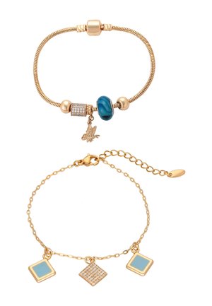 Bracelet à breloques ton or avec pierre bleue, breloque papillon et perle de strass ; bracelet chaîne doré avec breloques géométriques bleues et en strass.