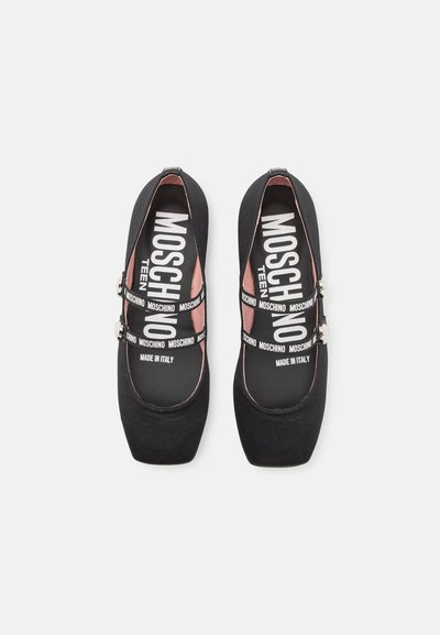 Bailarinas de tela negra con punta cuadrada, que cuentan con una plantilla rosa. Incluyen una correa con el logo repetitivo "Moschino" y acentos metálicos.