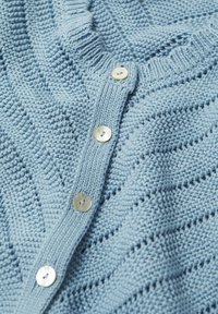 Lichtblauwe gebreide cardigan met een geribde kraag, voorzien van een getextureerd golvend patroon en vier ronde, lichtgekleurde knopen.