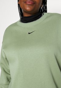 Ljusgrön sweatshirt med rund halsringning och långa ärmar. Har en liten svart Nike-logga framtill. Mjuk textur.