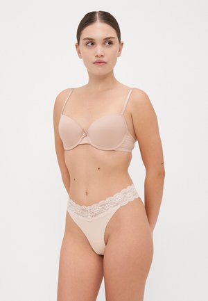 Beige gewatteerde beha van soepele stof, verstelbare bandjes en delicate kantafwerking. Bijpassende string met een kanten tailleband.