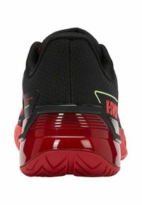Chaussure de sport noire avec une tige en mesh, des accents rouges, une semelle rouge brillante et un talon texturé, avec un détail de marque vert.