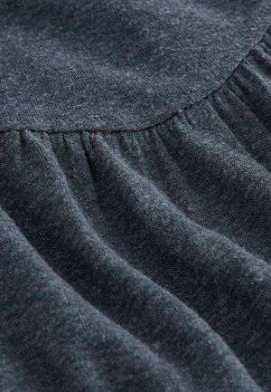 Tumši pelēks audums ar maigu tekstūru un savākšanas šuvju detaļām, demonstrējot drapējumus un smalkas krāsas variācijas visā virsmā.