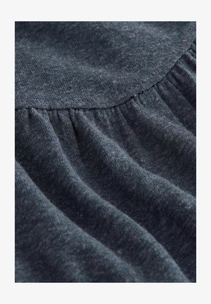 Tumši pelēks audums ar maigu tekstūru un savākšanas šuvju detaļām, demonstrējot drapējumus un smalkas krāsas variācijas visā virsmā.