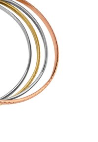 Four metallic bangles: one rose gold, one silver, one gold, and one brushed silver. They feature smooth and hammered textures in varying widths.
