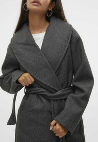 Abrigo envolvente de lana gris con un collar amplio y mangas largas, que presenta un cinturón atado en la cintura y una tela suave y texturizada.