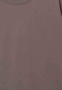 Smeđi pamučni T-shirt s okruglim izrezom. Tkanina izgleda mekano s glatkom teksturom, bez vidljivih uzoraka ili ukrasa.