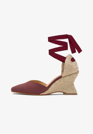 Alpargata cuña con puntera de tela burdeos, tacón trenzado de yute, parte trasera beige texturizada y lazos burdeos para atar al tobillo.