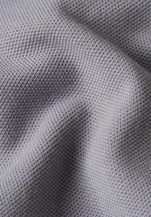 Close-up van lichtgrijze gebreide stof met gedetailleerde textuur en steekpatroon, met zachte plooien.