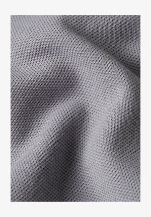 Close-up van lichtgrijze gebreide stof met gedetailleerde textuur en steekpatroon, met zachte plooien.