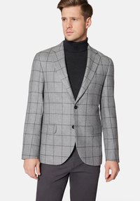 Szary marynarka w kratę wykonana z tkaniny tkanej, z zapięciem na dwa guziki, klapami typu notch i kieszeniami bocznymi; w zestawieniu z czarnym swetrem z golfem.