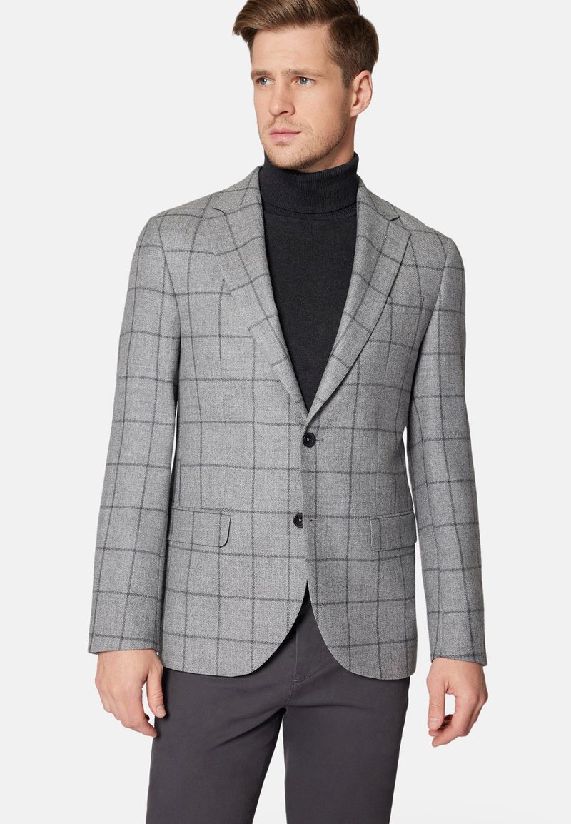 Szary marynarka w kratę wykonana z tkaniny tkanej, z zapięciem na dwa guziki, klapami typu notch i kieszeniami bocznymi; w zestawieniu z czarnym swetrem z golfem.