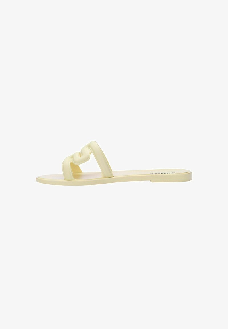 Chancla de goma en un suave amarillo con diseño de doble tira interconectada. Suela plana con textura suave, estilo minimalista.