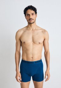 Boxer briefs blu con una vita nera che presenta il logo "BJÖRN BORG". Tessuto morbido e design aderente con una texture liscia.