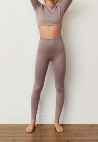 Dwu-częściowy, prążkowany zestaw sportowy w delikatnym kolorze mauve, składający się z krótkiego topu z długim rękawem oraz legginsów z wysokim stanem. Gładka faktura, dopasowany krój.