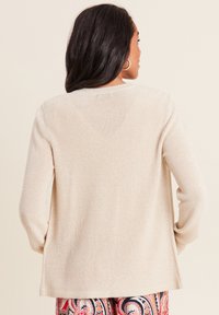 Maglione beige a coste con vestibilità comoda, scollatura rotonda e maniche lunghe, caratterizzato da una superficie leggermente testurizzata.