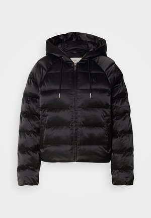 Juodas pūkuotas džemperis su gaubtu, turi užtrauktuką priekyje, elastingus rankogalius ir lygų, blizgų paviršių. Ant krūtinės yra logotipo detalė.