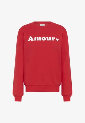 Rode trui met lange mouwen en ronde hals, met het woord "Amour" en een klein wit hartje in witte letters over de borst.