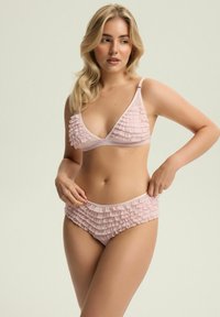 Jasnoróżowy zestaw bikini z falbaniastymi detalami na biustonoszu i majtkach. Biustonosz ma regulowane ramiączka oraz trójkątny kształt. Delikatny materiał.