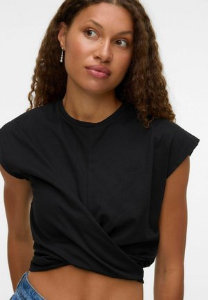 Zwarte T-shirt met korte mouwen en een gedraaide voorkant, gemaakt van zachte stof. Hoge halslijn en cropped pasvorm, gecombineerd met blauwe denimonderdelen.