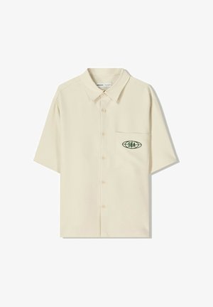 Beige overhemd met korte mouwen, gemaakt van lichtgewicht stof, voorzien van een borstzak met een groen geborduurd logo en een knoopsluiting aan de voorkant.