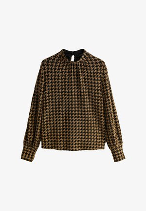 Blus med lång ärm som har ett svart och guld hounds-tooth mönster, med hög krage och en nyckelhålsdetalj på baksidan. Slät textur.