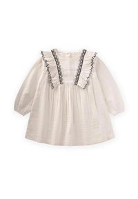 Robe en coton blanc à manches longues, bordure noire à volants le long de l'encolure, et corsage froncé pour une silhouette fluide.